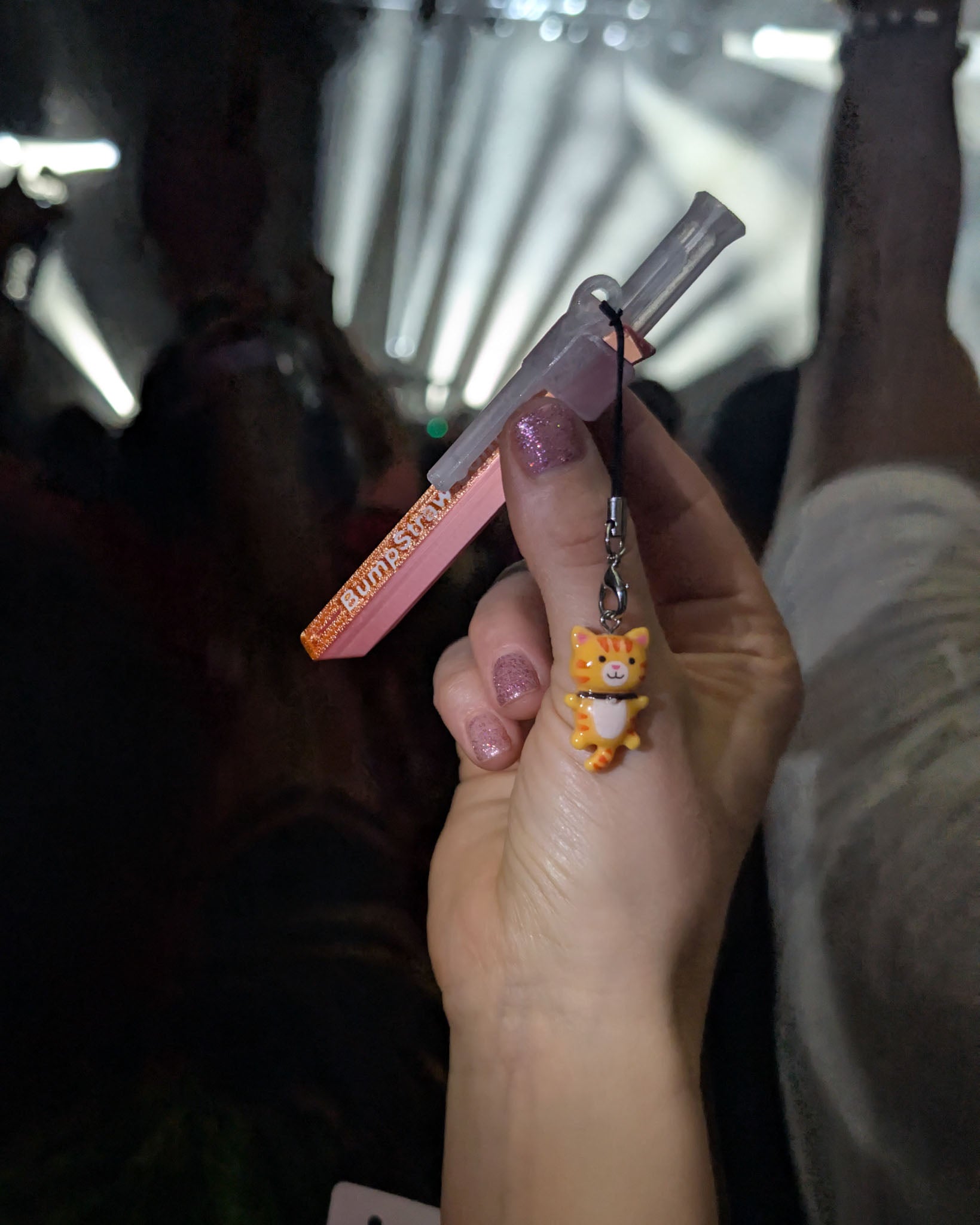 Orange BumpStraw bump straw powder spoon with cat charm held at a concert, perfect for cacao and fine powders